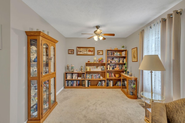 sitting room with carpet floors, a textured ceiling, and a ceiling fan