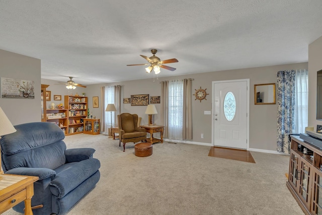 carpeted living area featuring baseboards, a textured ceiling, and ceiling fan