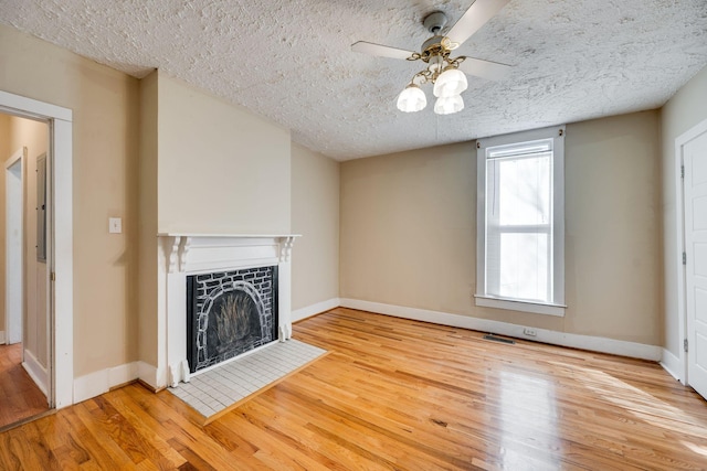 4509 Wyoming Ave, Nashville, TN 37209 - unfurnished living room featuring wood finished floors, baseboards, a fireplace with flush hearth, ceiling fan, and a textured ceiling