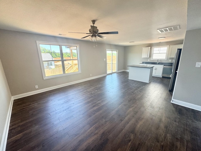 153 Cardinal Crk, Clarksville, TN 37040 - unfurnished living room featuring ceiling fan, healthy amount of natural light, dark wood-type flooring, baseboards, and a textured ceiling