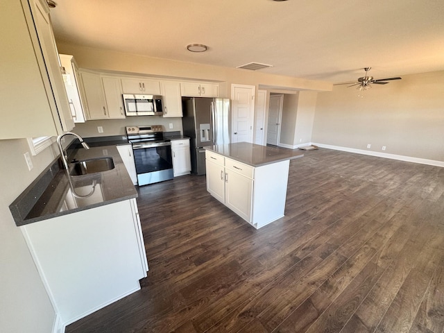 153 Cardinal Crk, Clarksville, TN 37040 - kitchen with stainless steel appliances, a sink, dark countertops, a center island, and dark wood finished floors
