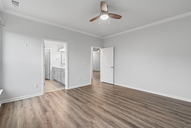 unfurnished bedroom with visible vents, baseboards, ornamental molding, wood finished floors, and ensuite bathroom