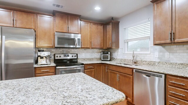 1504 Rockwood Ln, Lebanon, TN 37087 - kitchen with visible vents, a sink, appliances with stainless steel finishes, decorative backsplash, and light stone countertops