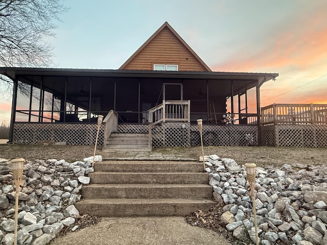 view of front of property featuring log veneer siding, stairs, and a sunroom