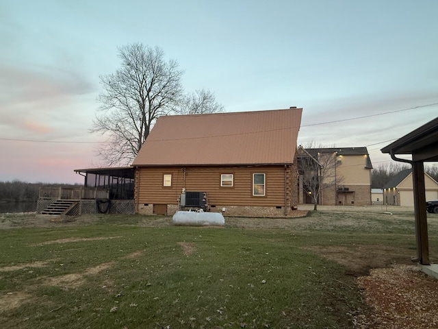 back of house at dusk with crawl space, metal roof, a yard, and central AC unit