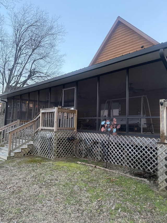rear view of house featuring faux log siding, a yard, and a sunroom