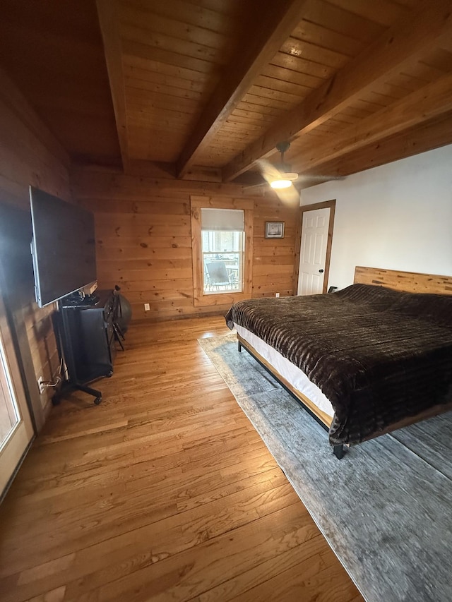 bedroom featuring wood finished floors, ceiling fan, wood walls, wooden ceiling, and beamed ceiling