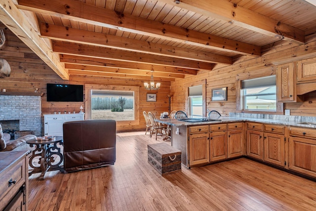 kitchen with light wood-type flooring, beamed ceiling, an inviting chandelier, and open floor plan