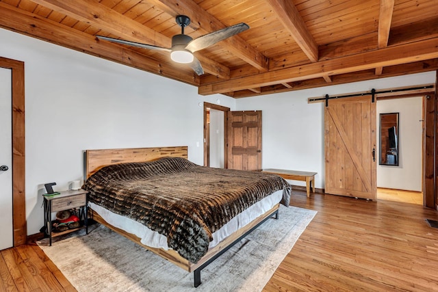 bedroom with a barn door, wood ceiling, wood finished floors, and beamed ceiling