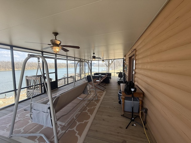 sunroom / solarium with ceiling fan and a water view