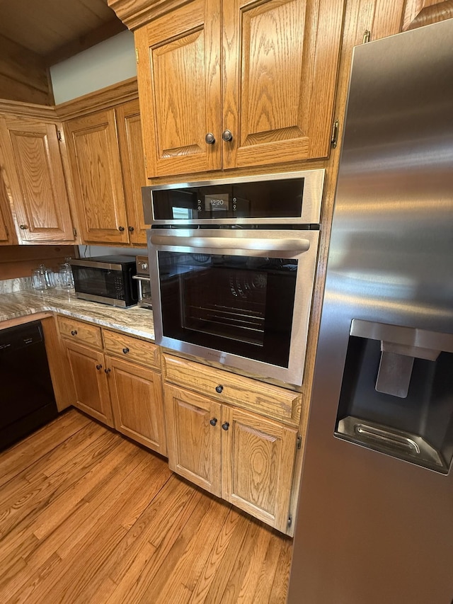 kitchen with light wood-style flooring, stainless steel appliances, and brown cabinets