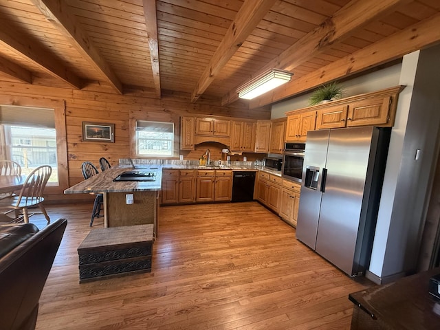 kitchen featuring light wood finished floors, a sink, black appliances, wood ceiling, and wood walls