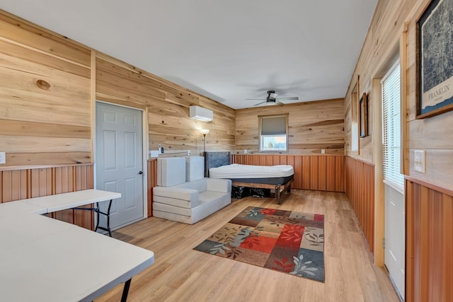 bedroom featuring wooden walls, a wall unit AC, and wood finished floors