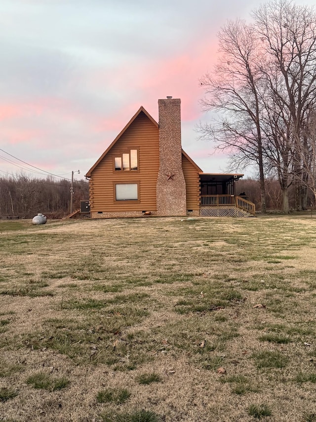 back of house featuring a yard, log exterior, and a chimney