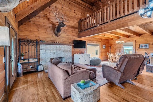 living room with beam ceiling, an inviting chandelier, and wood walls