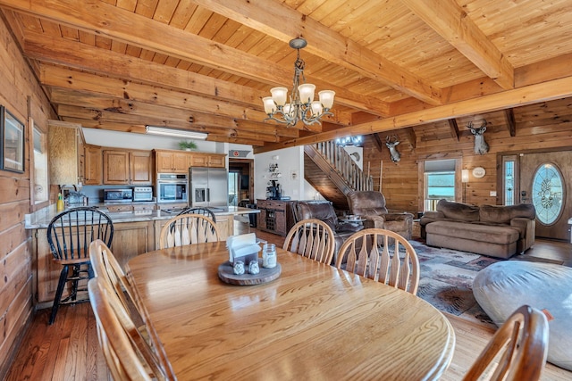 dining area featuring hardwood / wood-style floors, a notable chandelier, wood ceiling, and wood walls