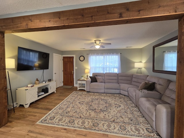 living area featuring ceiling fan, baseboards, a textured ceiling, and wood finished floors