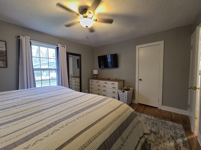 bedroom with ceiling fan, wood finished floors, baseboards, and a textured ceiling