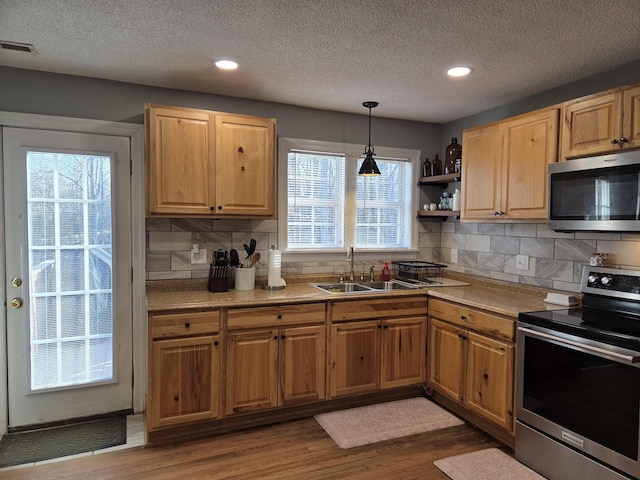 kitchen featuring dark wood-style floors, visible vents, a sink, appliances with stainless steel finishes, and backsplash