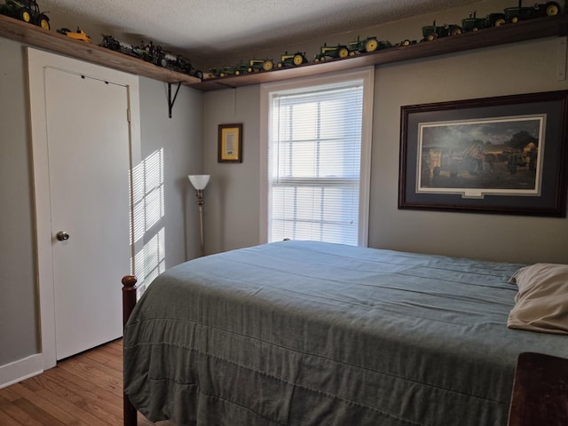 bedroom with wood finished floors and a textured ceiling