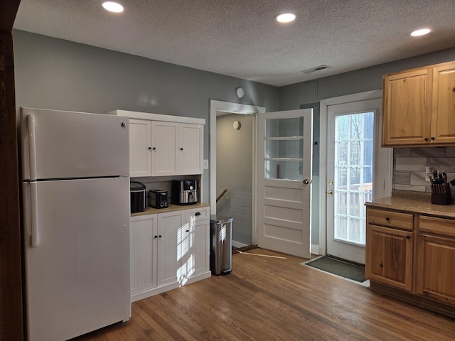 kitchen with tasteful backsplash, wood finished floors, visible vents, and freestanding refrigerator