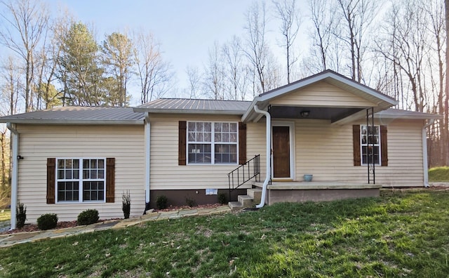 ranch-style home with metal roof, covered porch, and a front lawn