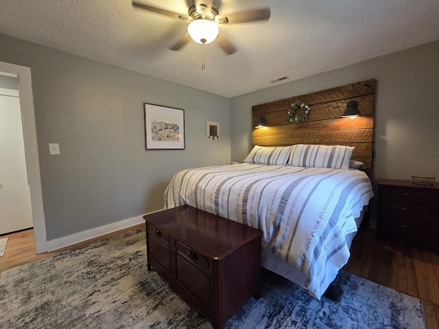 bedroom featuring visible vents, baseboards, a textured ceiling, and wood finished floors