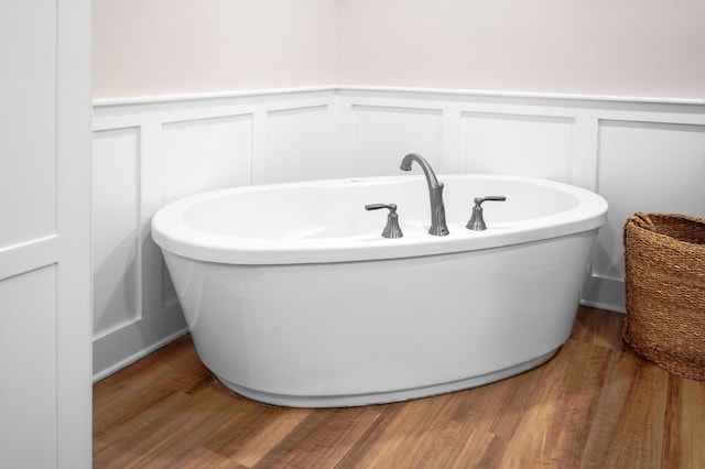 full bath featuring wainscoting, wood finished floors, and a freestanding tub