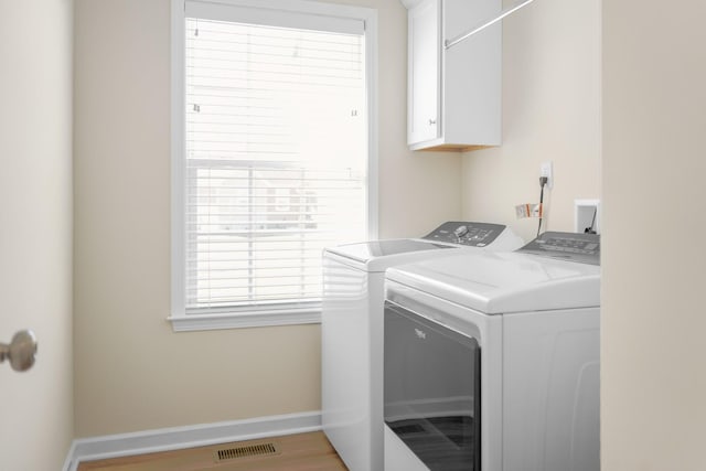 clothes washing area with baseboards, cabinet space, visible vents, and washer and clothes dryer