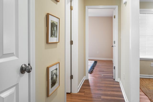 corridor with dark wood-type flooring and baseboards