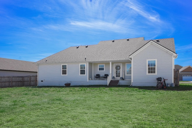 rear view of property featuring a lawn, roof with shingles, and fence