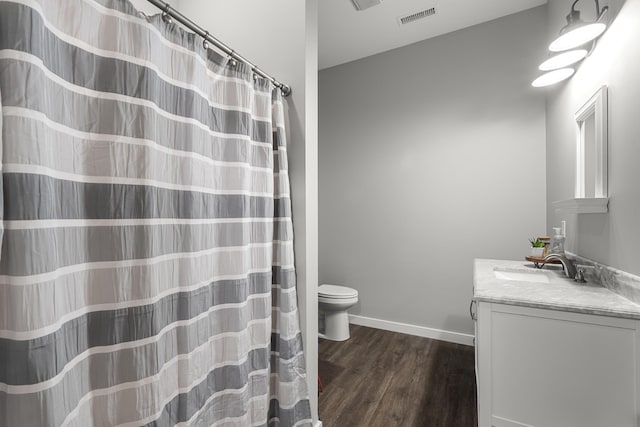 bathroom with visible vents, baseboards, toilet, wood finished floors, and vanity