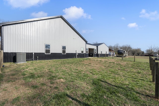 view of yard with an outbuilding, fence, and central AC