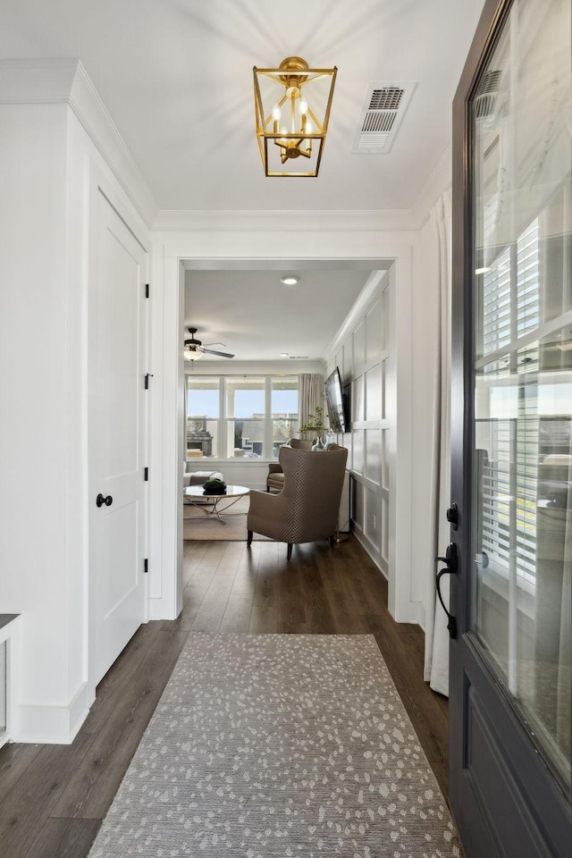foyer entrance with visible vents, crown molding, and dark wood-type flooring