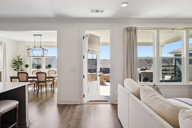 living area featuring visible vents, a healthy amount of sunlight, and dark wood-style flooring