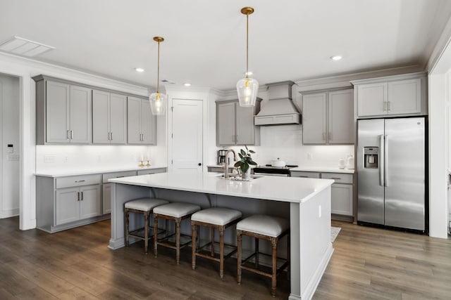 kitchen with stainless steel appliances, gray cabinetry, a breakfast bar area, and custom range hood
