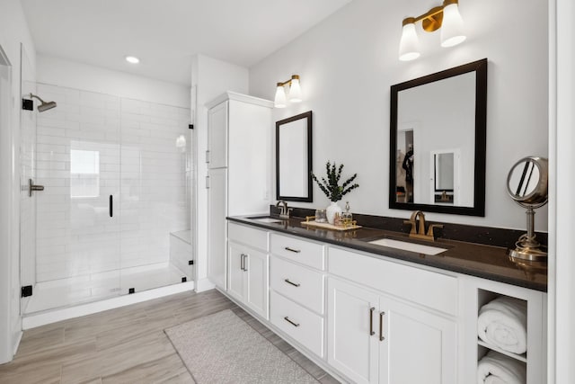 bathroom with a shower stall, recessed lighting, double vanity, and a sink