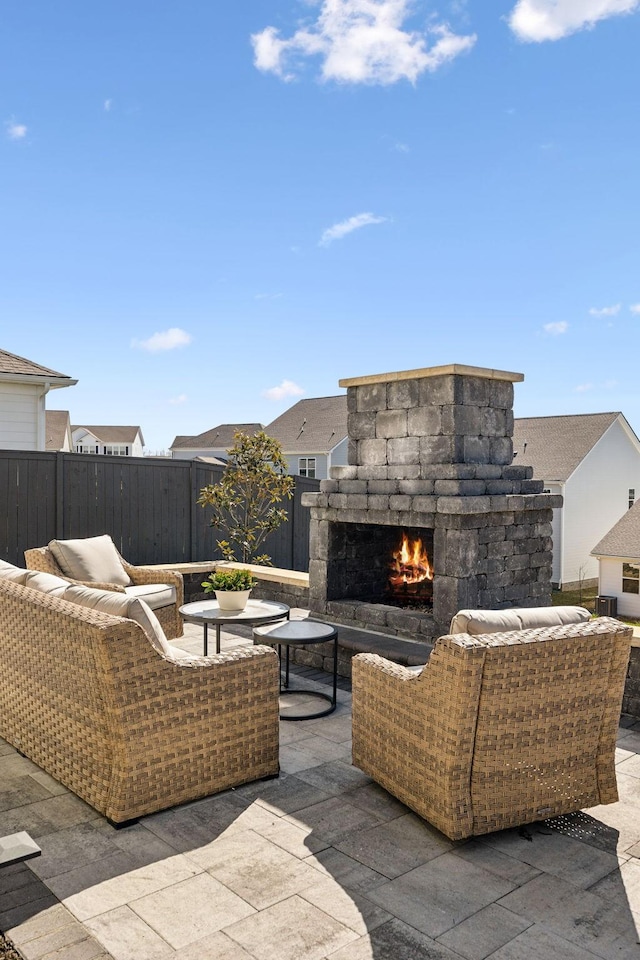 view of patio / terrace with an outdoor living space with a fireplace and fence