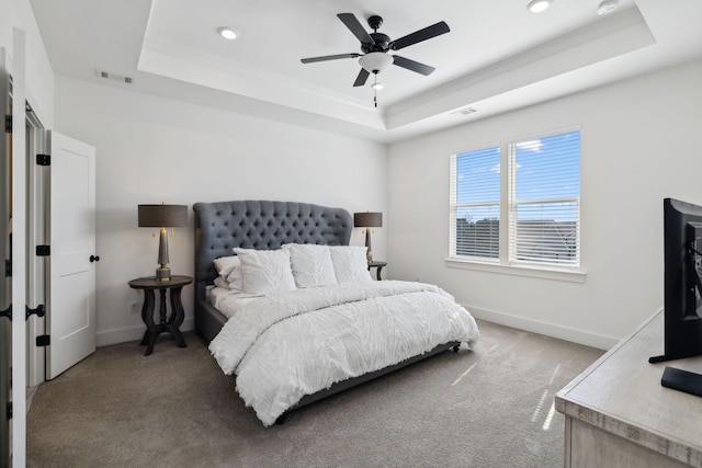 bedroom featuring baseboards, a tray ceiling, carpet floors, and visible vents