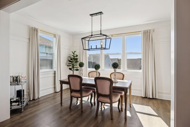 dining room featuring dark wood-style floors, a notable chandelier, and a decorative wall