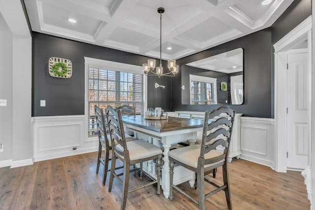 dining space with an inviting chandelier, beam ceiling, wood finished floors, and coffered ceiling