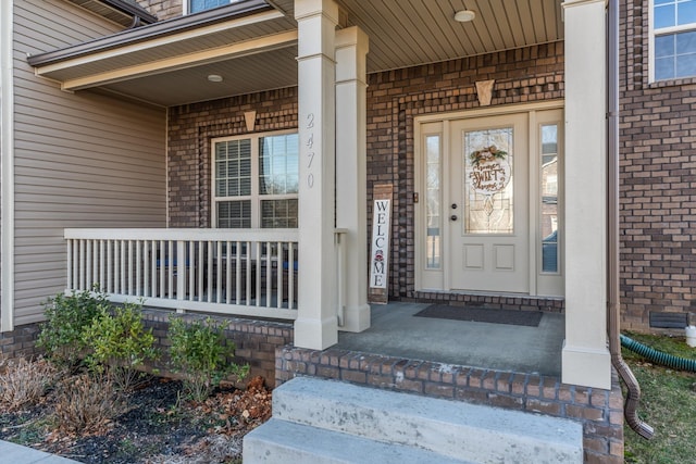 entrance to property with brick siding and covered porch