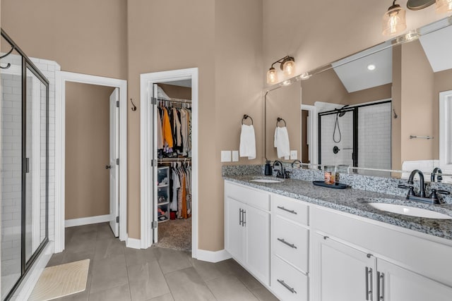 full bathroom featuring double vanity, a shower stall, a spacious closet, and a sink