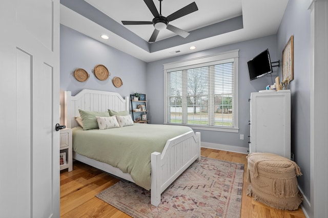bedroom featuring visible vents, a raised ceiling, light wood-style flooring, recessed lighting, and baseboards
