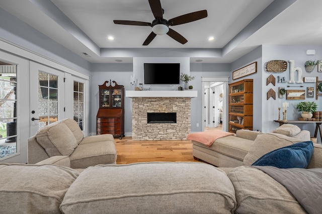 living room with french doors, a raised ceiling, a ceiling fan, and wood finished floors