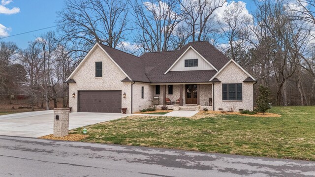 view of front of house featuring brick siding, a front yard, roof with shingles, a garage, and driveway
