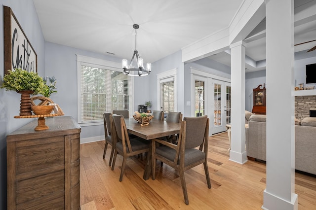 dining room featuring visible vents, baseboards, light wood-style floors, a notable chandelier, and ornate columns