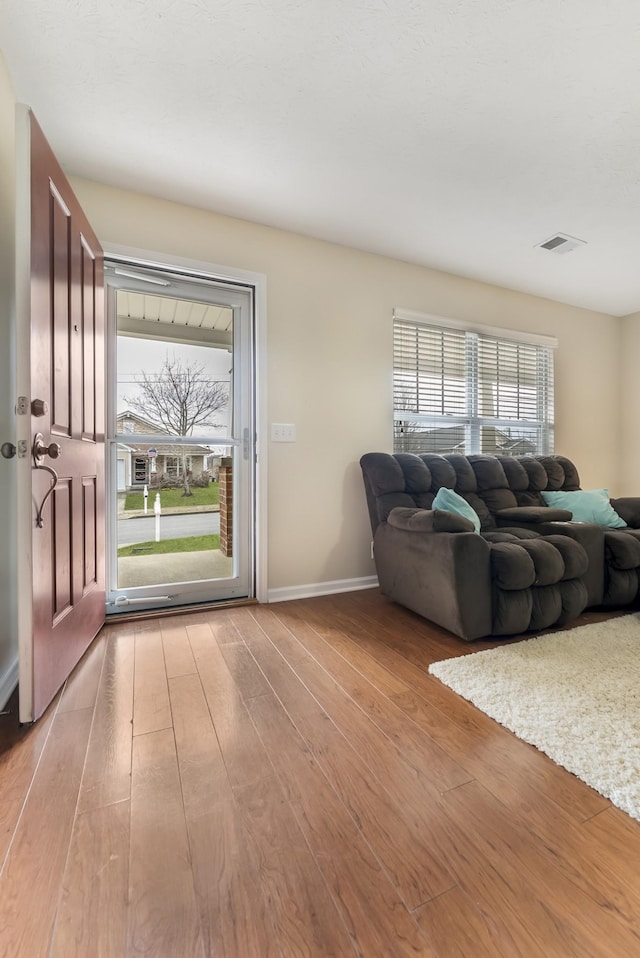 living area with visible vents, wood-type flooring, and baseboards