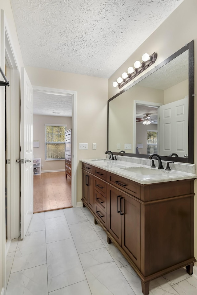 ensuite bathroom with marble finish floor, ensuite bathroom, a sink, double vanity, and ceiling fan