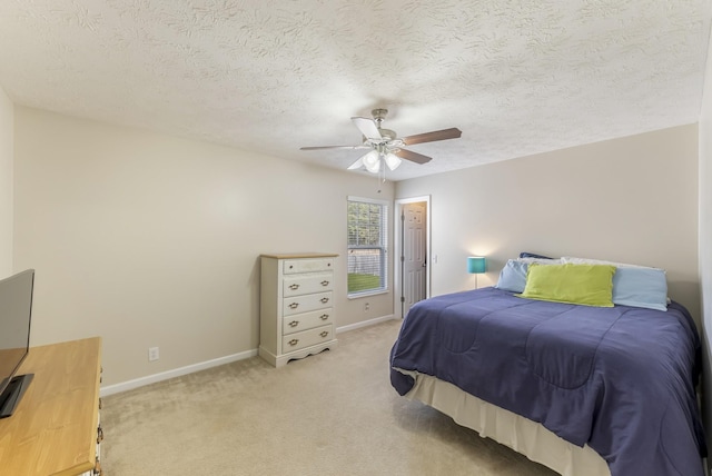 bedroom featuring a textured ceiling, a ceiling fan, baseboards, and light carpet